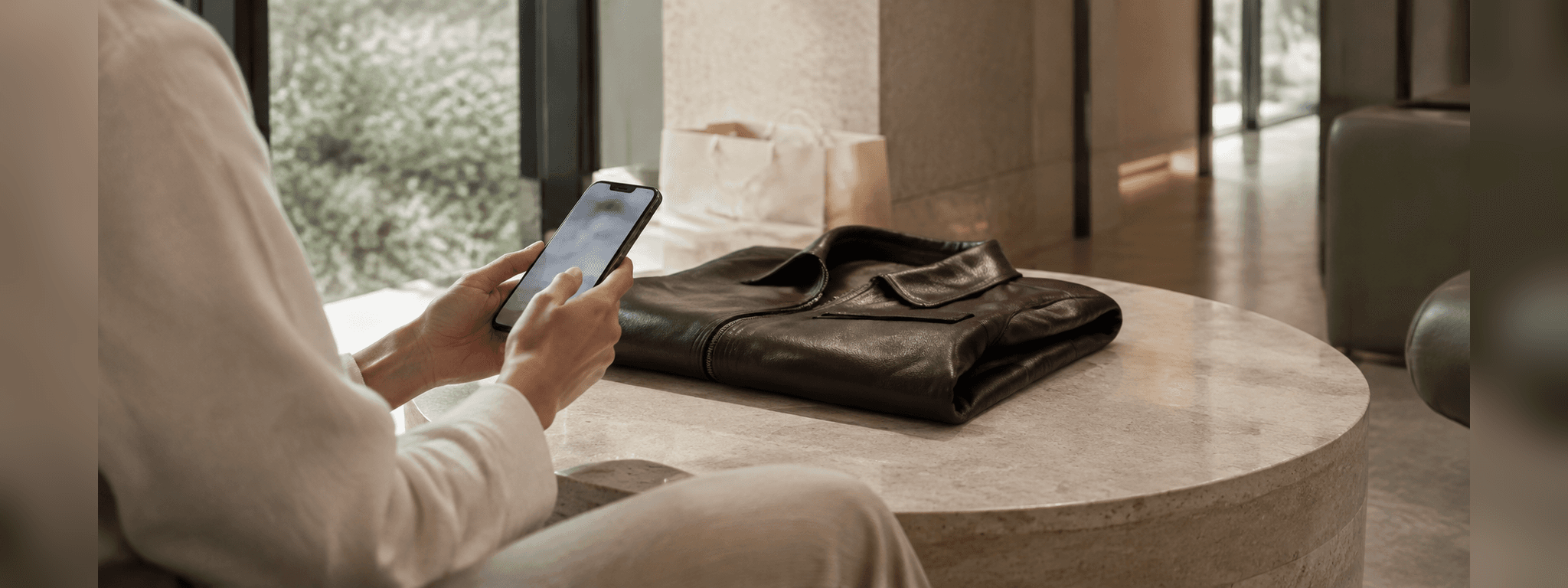 A client reviewing a selection on their phone beside a leather jacket after a store visit